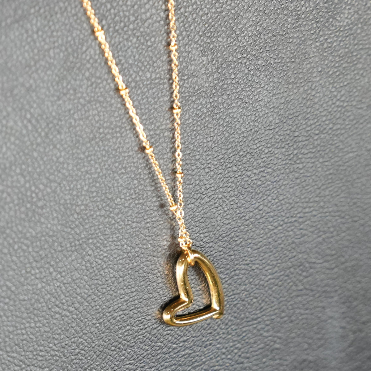SMITTEN Gold : Une fine chaîne perlée retenant un pendentif en forme de cœur abstrait